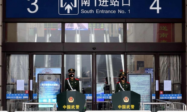 우한에서 새로운 코로나 바이러스가 발생한 후 도시가 문을 닫은 후 마스크를 착용 한 중국 준 군사 관들이 폐쇄 된 한 커우 기차역 입구에 경비를 서고있다. 사진 : China Daily / Reuters