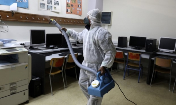 방호복을 입고 있는 노동자가 아테네의 한 고등학교 교실에서 소독제를 뿌리고 있다. / AP